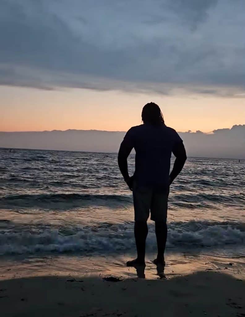 wide angle of James Sanders overlooking a bay at dawn